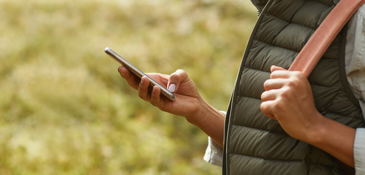Photo of someone walking and checking a cell phone.